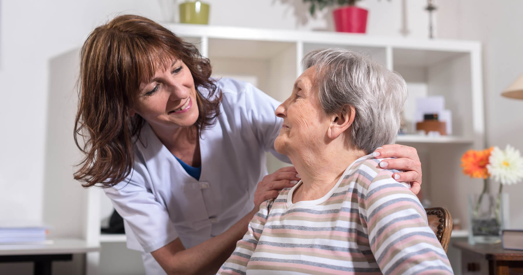 Pflegekraft spricht mit einer Seniorin